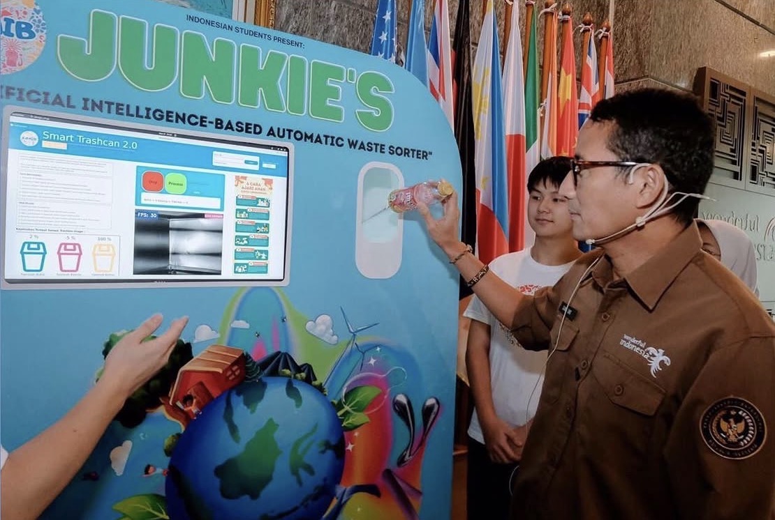Indonesia's Minister of Tourism Sandiaga Uno demonstrating JUNKIES — KOMIB's AI-powered automatic waste sorter — by feeding a plastic bottle into the unit.